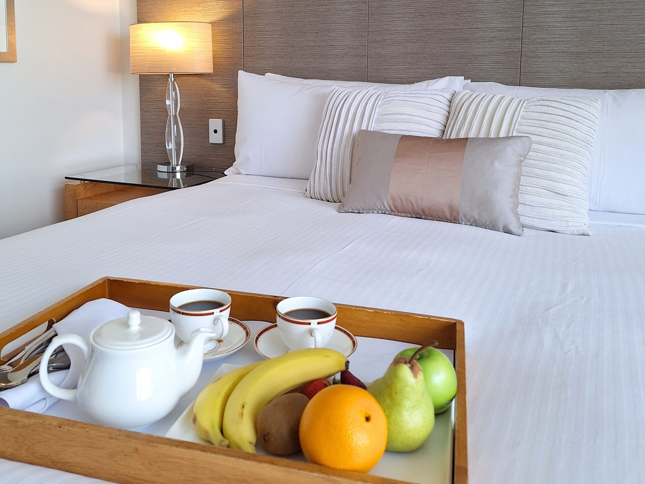 Coffee and fruits on top of the bed
