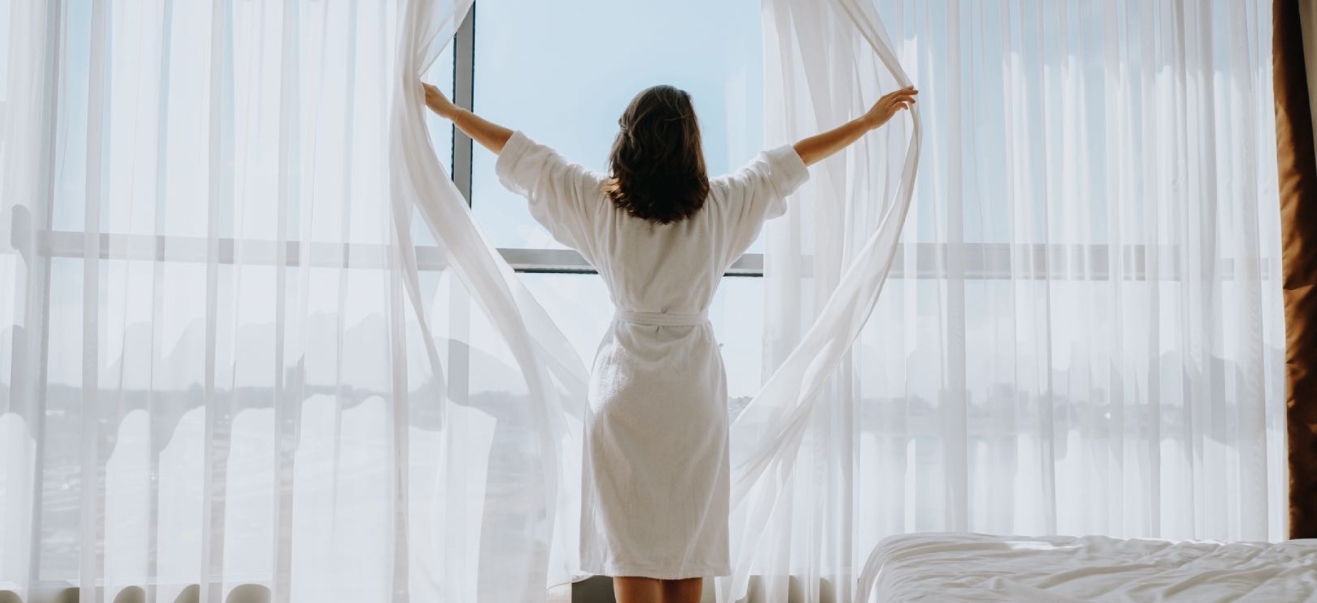 Woman opening sheer curtains
