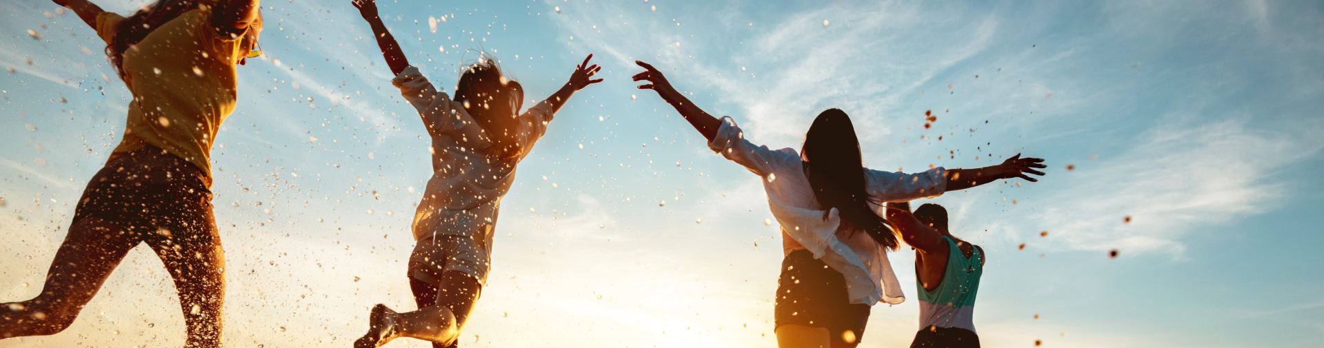 Joyful friends jumping at sunset